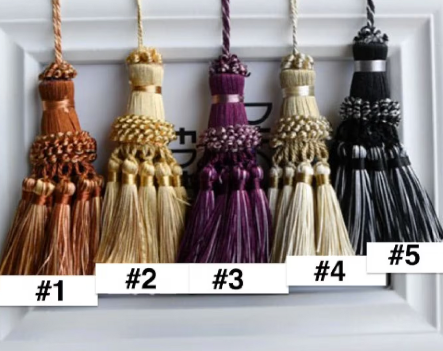 Five decorative tassels in different colors on a white background